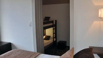 Habitación de hotel con literas, una mesita de noche, una lámpara y suelo alfombrado.
