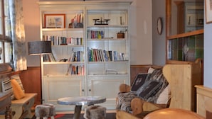 Un salón acogedor con un sillón de cuero, una estantería y una mesa redonda.