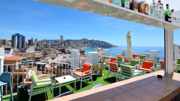 A balcony with outdoor seating and a view of a cityscape and the sea. - Hotel Queens (Benidorm)