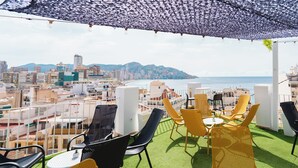 A rooftop terrace with outdoor seating and a city view. - Hotel Queens (Benidorm)