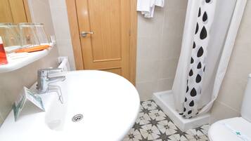 A bathroom with a white sink, a shower with a black and white polka dot curtain, and a toilet.