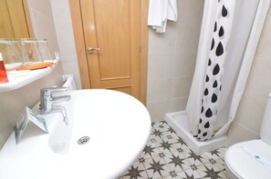 A bathroom with a white sink, a shower with a black and white polka dot curtain, and a toilet.