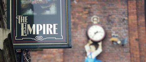 A pub sign with "The Empire" and "Guinness Time" on a brick wall.