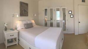 A bedroom with a bed, bedside tables, a chair, a TV, and a wardrobe.