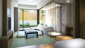 Un baño moderno con cabina de ducha de vidrio, tocador de madera y un rincón de descanso con mesa y cojines.
