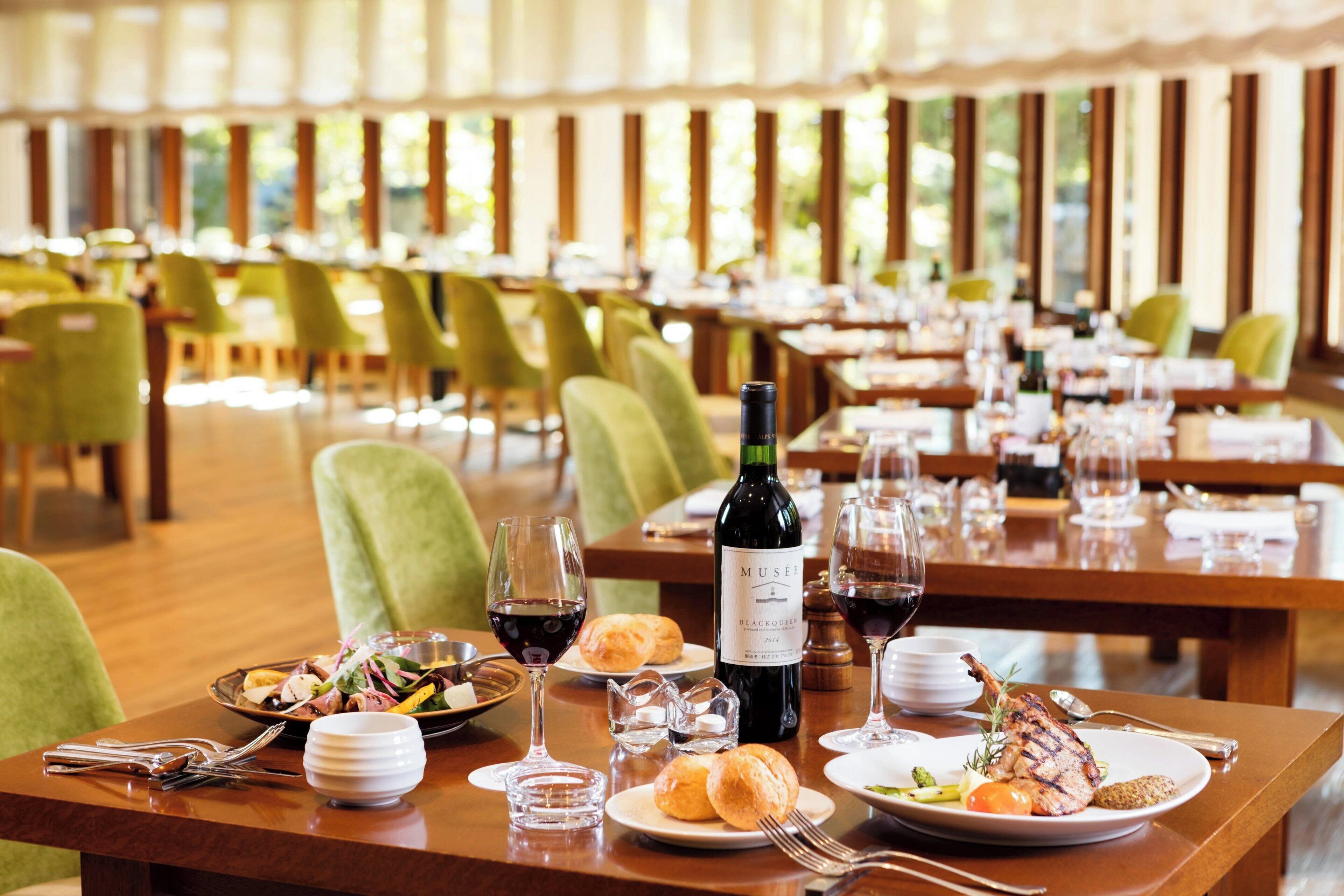 A dining area with tables set for meals, wine glasses, and a bottle of wine.