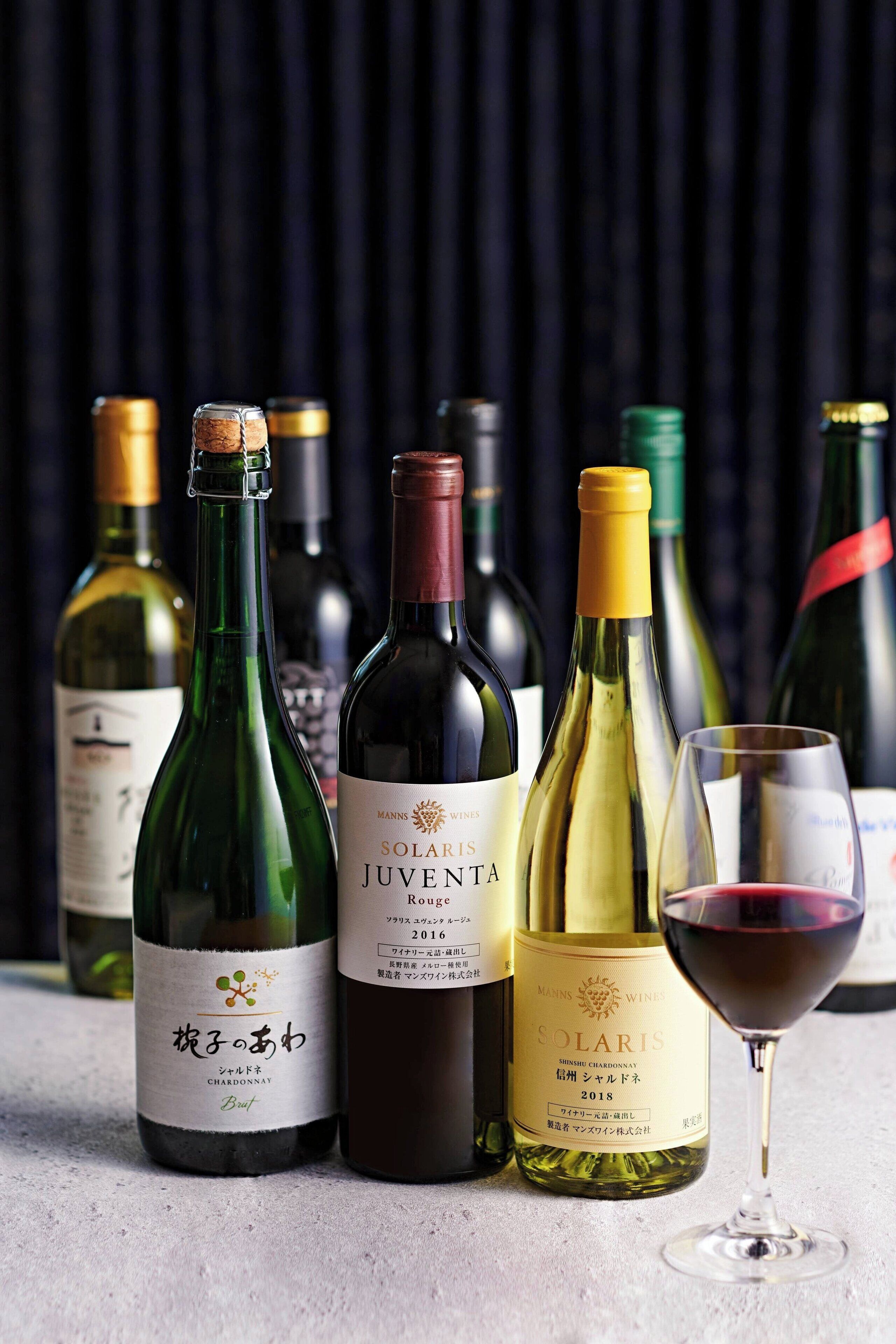Une sélection de bouteilles de vin et un verre à vin sont posés sur une table.