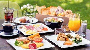 A breakfast buffet with various dishes, drinks, and a coffee setup on a wooden table.