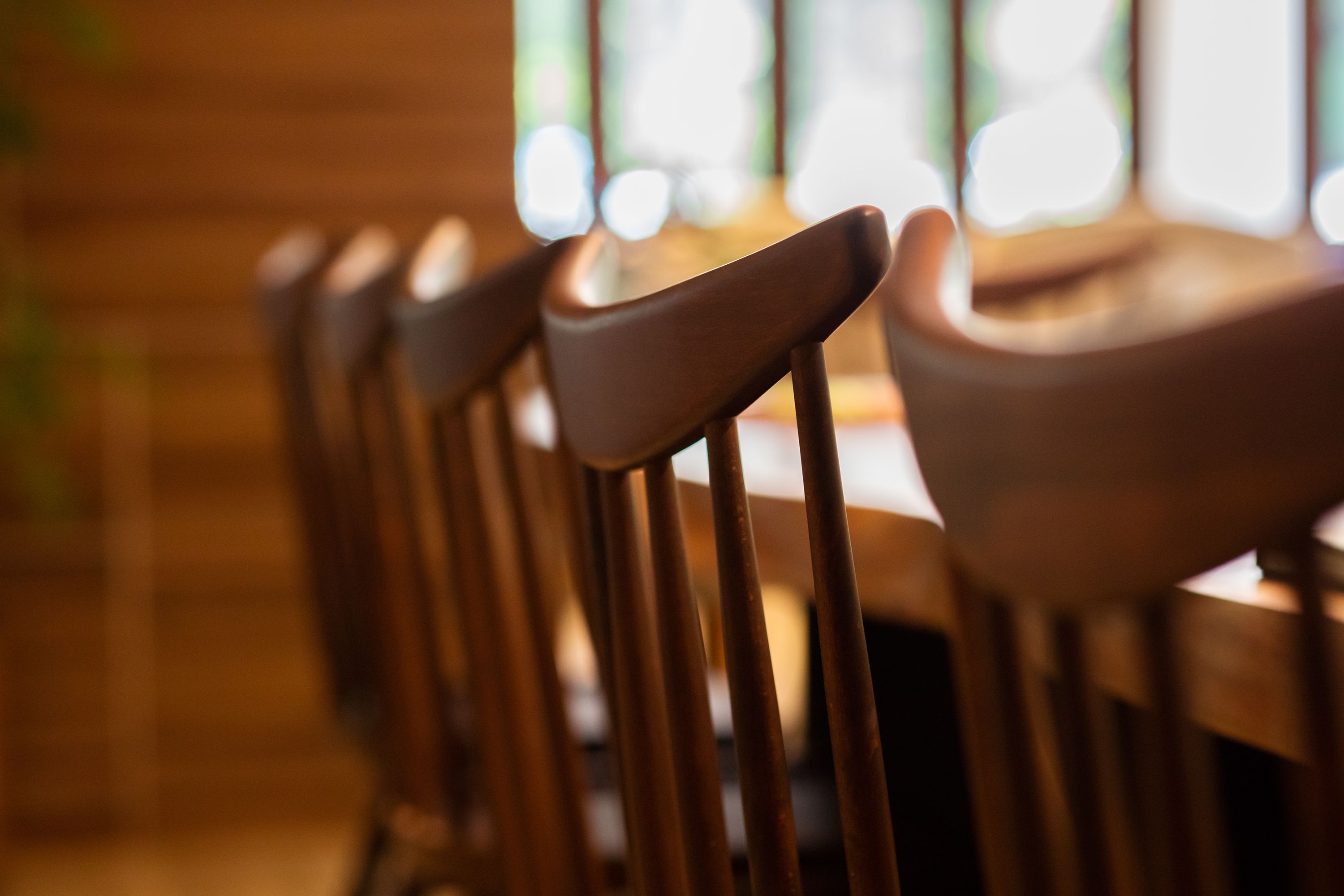 Een rij houten stoelen voor een onscherpe achtergrond.