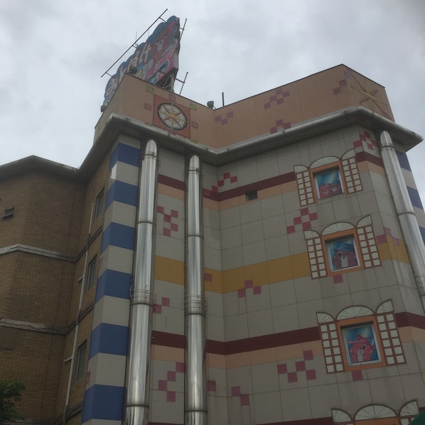 A building with a colorful facade, large vertical pipes, and a clock on the top.