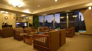 A modern hotel lobby with a seating area, large windows, and a view of the cityscape. - Hotel New Nishino (Kagoshima)