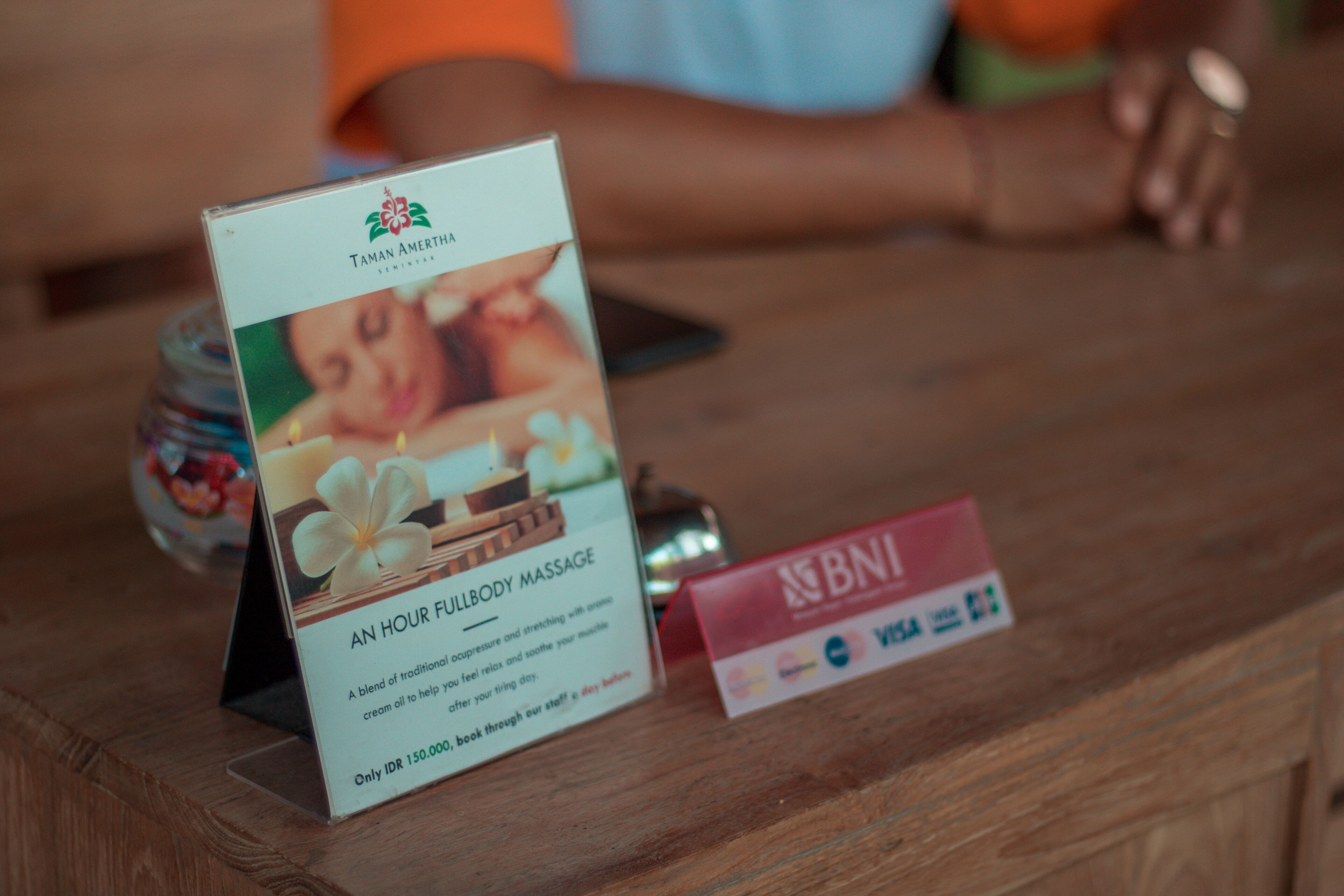 Mostrador de recepción con anuncio de masajes y señal de tarjeta de crédito BNI.