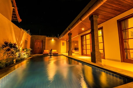 Una piscina al aire libre, sombrillas, sillones reclinables de piscina