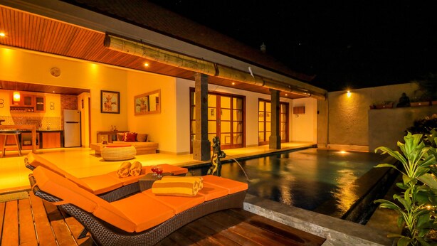 Un espacio exterior bien iluminado con piscina, terraza de madera y zona de estar.