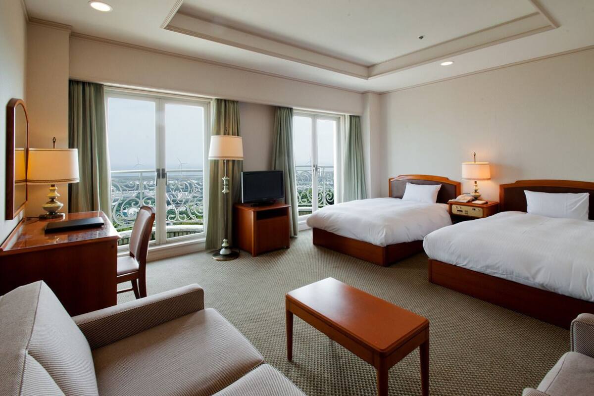 Una habitación de hotel con dos camas, un escritorio, una silla y un televisor.