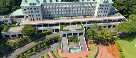 A large, multi-story hotel with a central courtyard, surrounded by lush greenery.