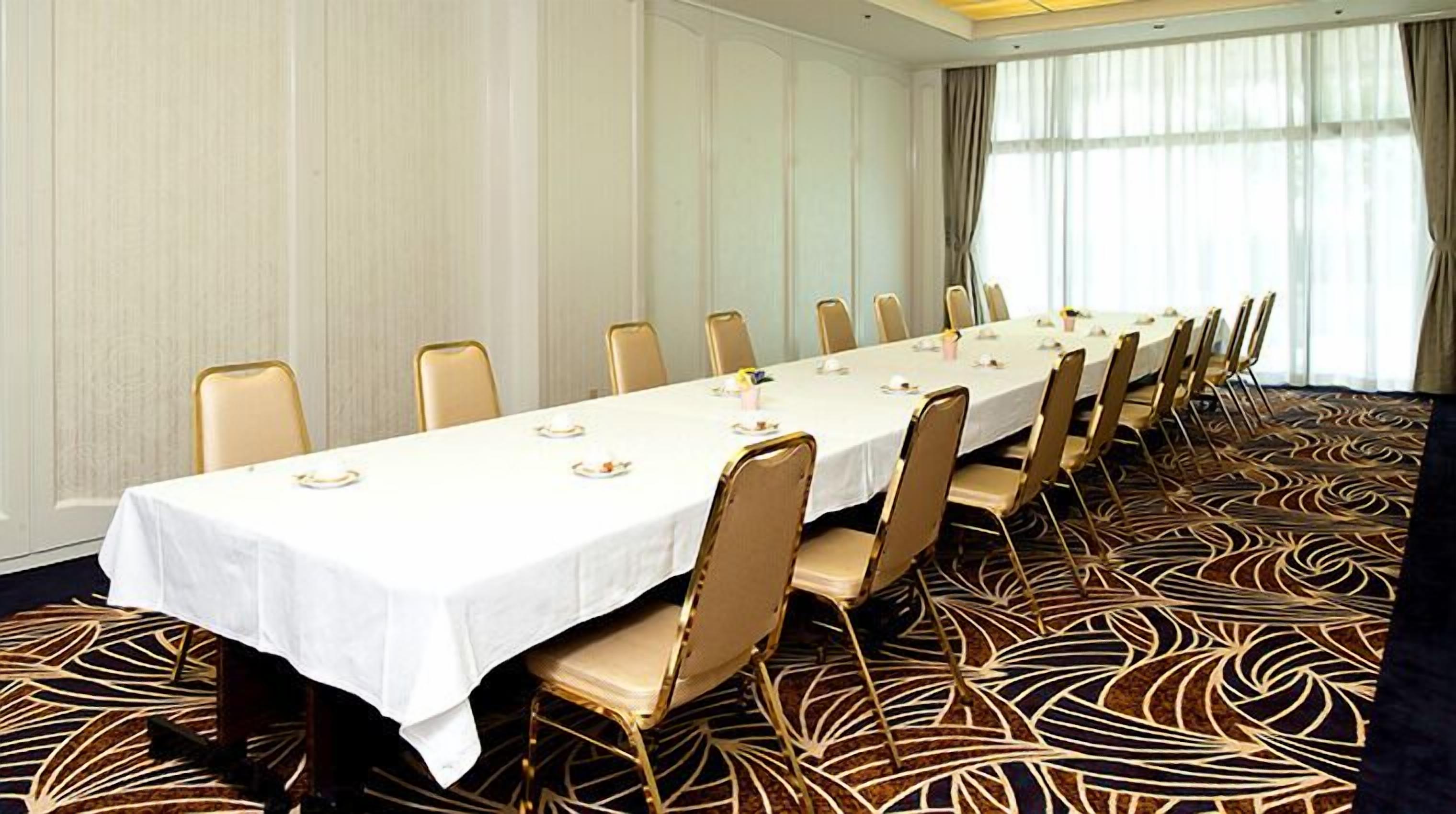A conference room with a long table, chairs, and a patterned carpet.