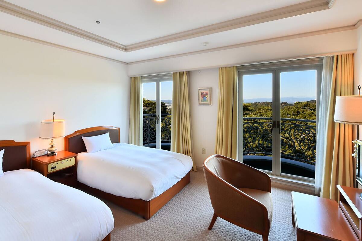 Una habitación de hotel con dos camas, un escritorio, una silla y un televisor.