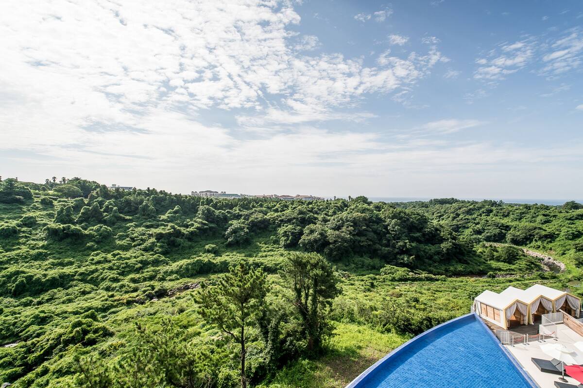 A poolside area with a view of a lush green landscape and distant buildings.