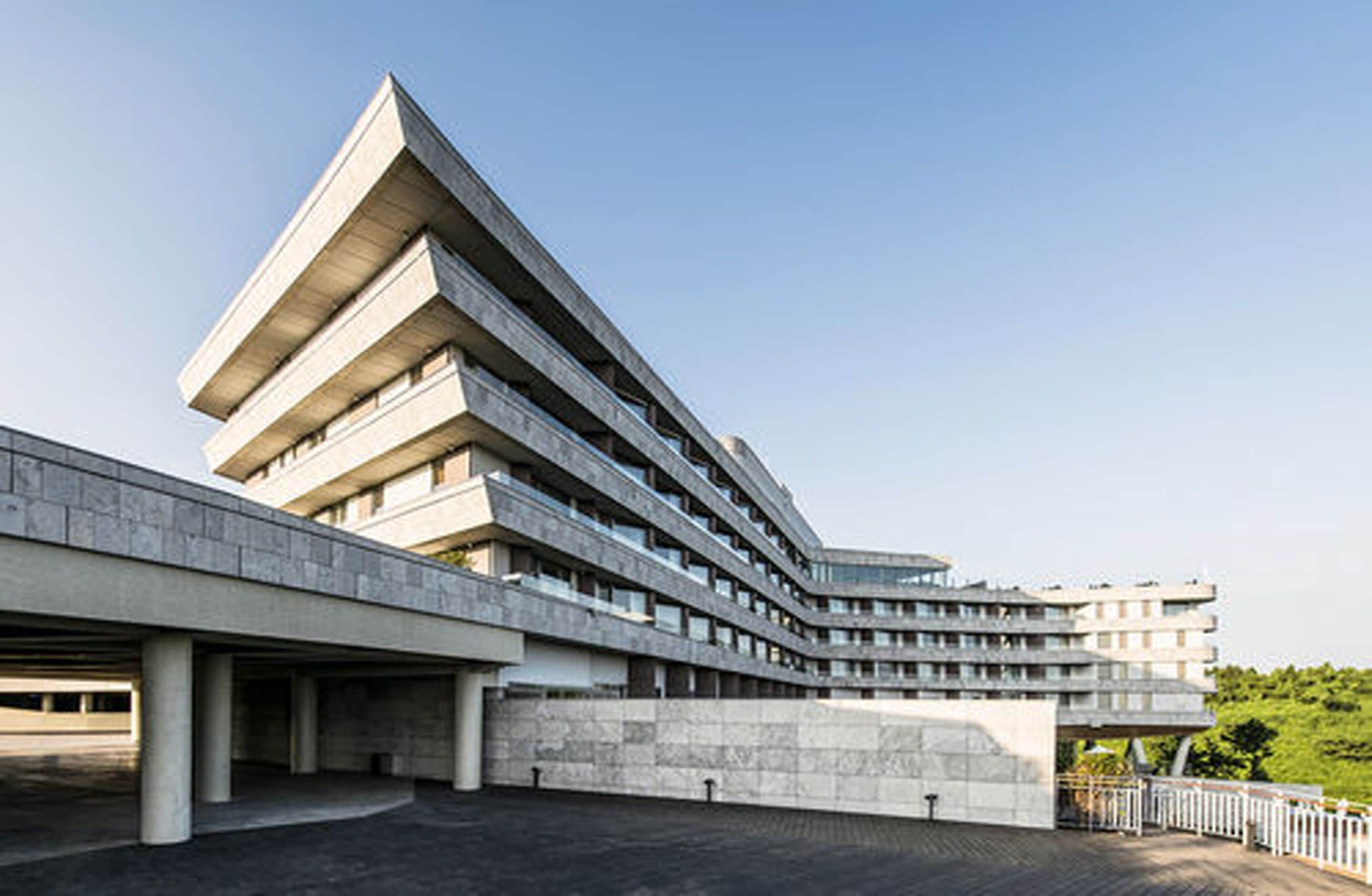 A modern building with a unique angular design, featuring multiple levels and a prominent overhang.