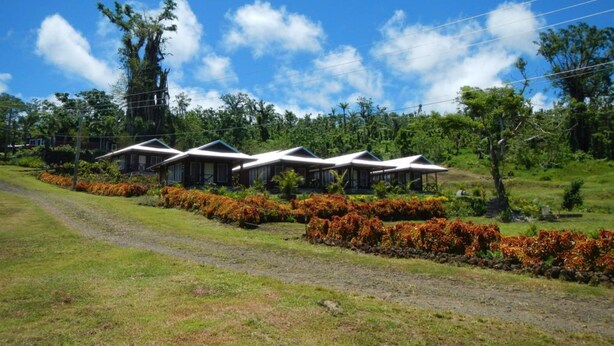 A row of modern, white-roofed cabins with a grassy foreground and a clear blue sky. - Tiavi Mountain Cabins (Siumu)