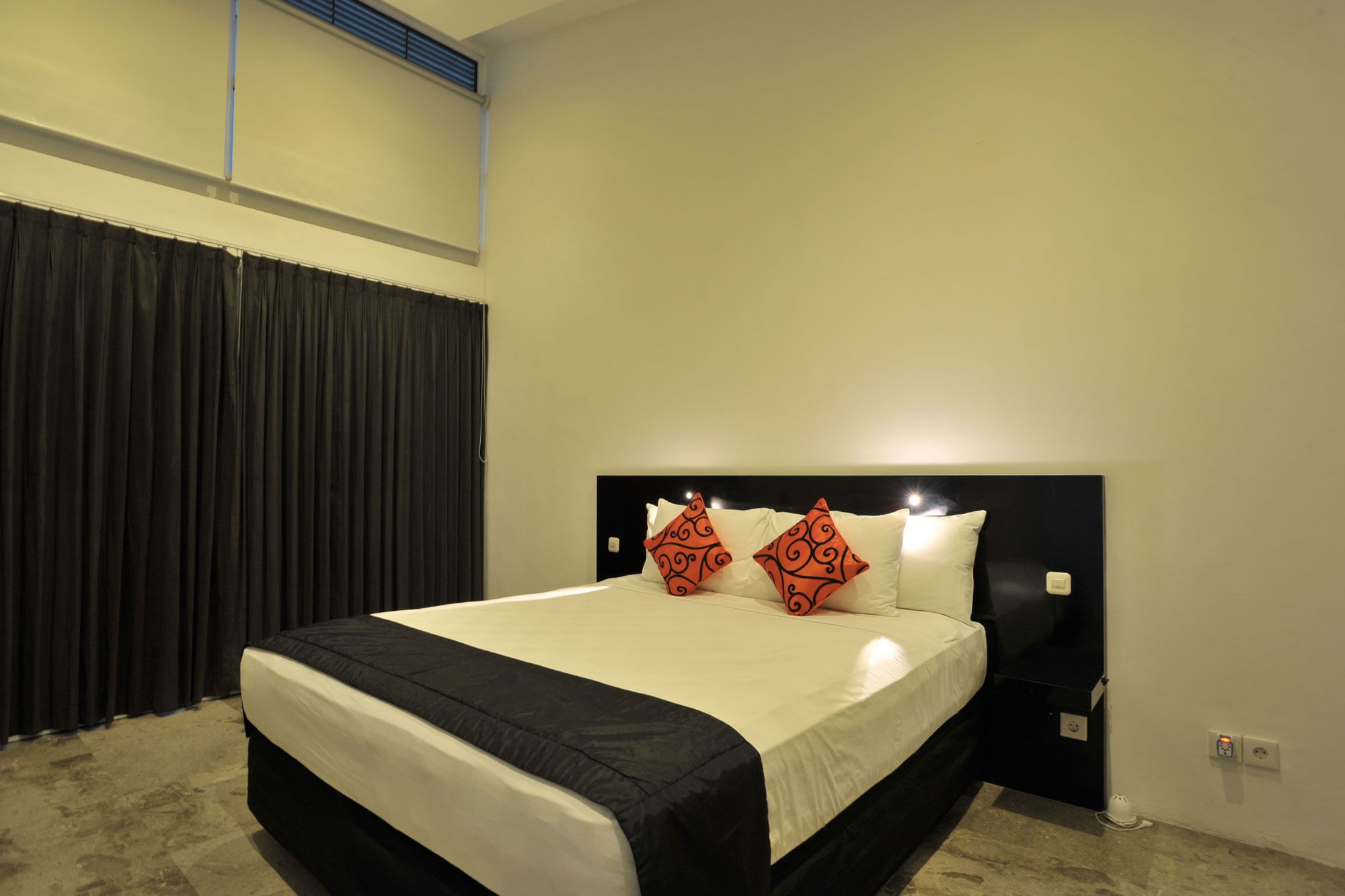 Une chambre d’hôtel avec un grand lit, une literie aux couleurs noir et blanc et deux coussins décoratifs.