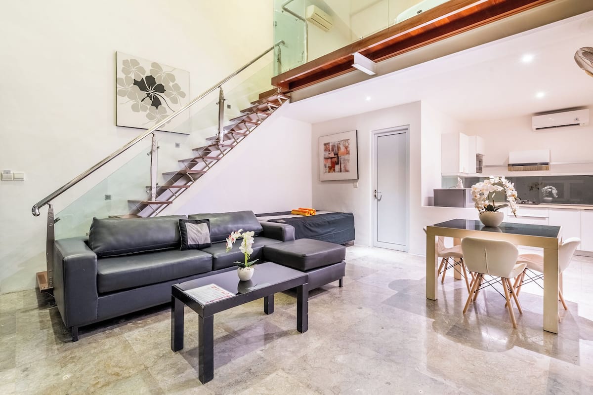 A modern living room with a sofa, coffee table, and a staircase leading to an upper floor.