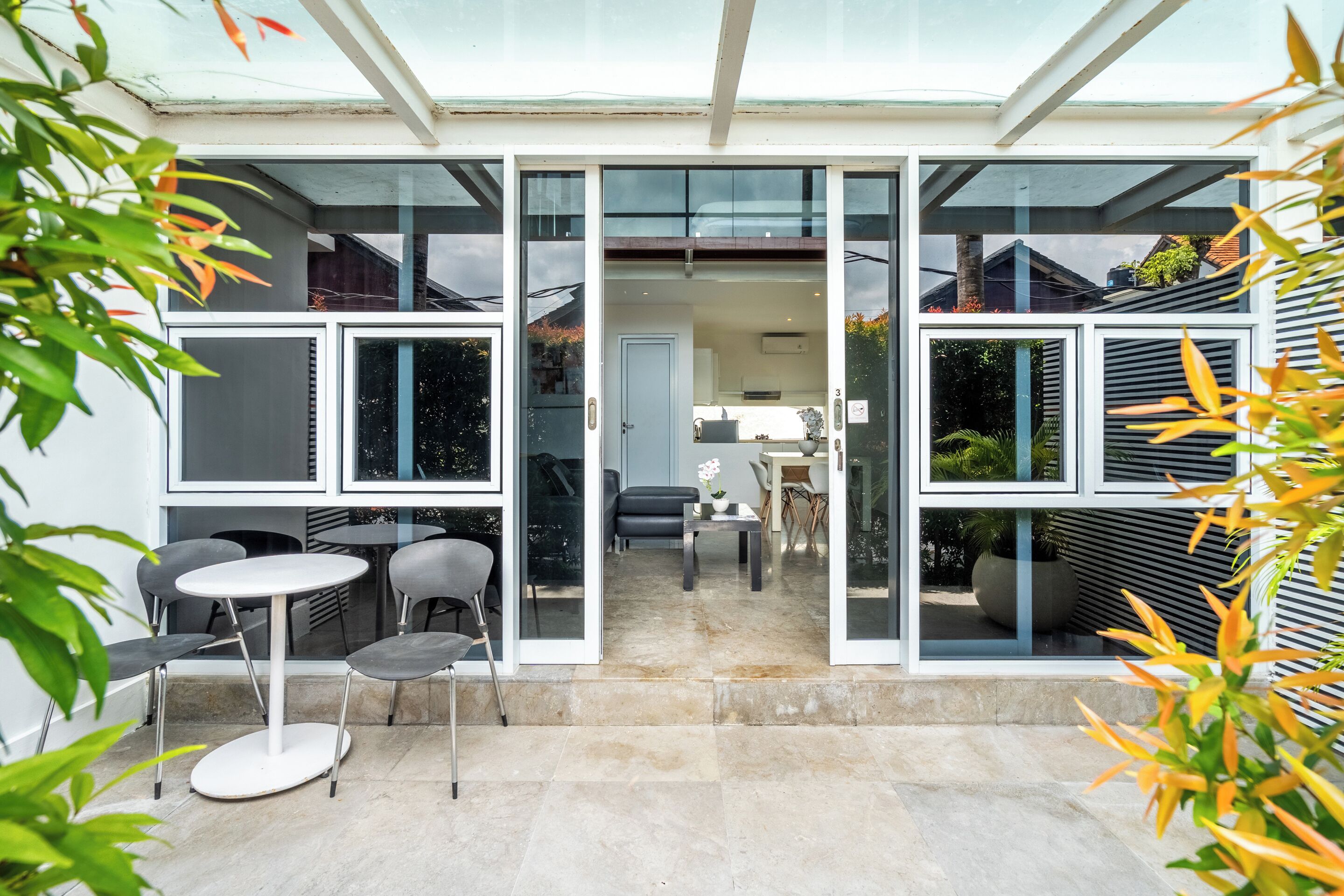 Une maison moderne dotée d’une porte vitrée donnant sur un patio aménagé avec une table et des chaises.