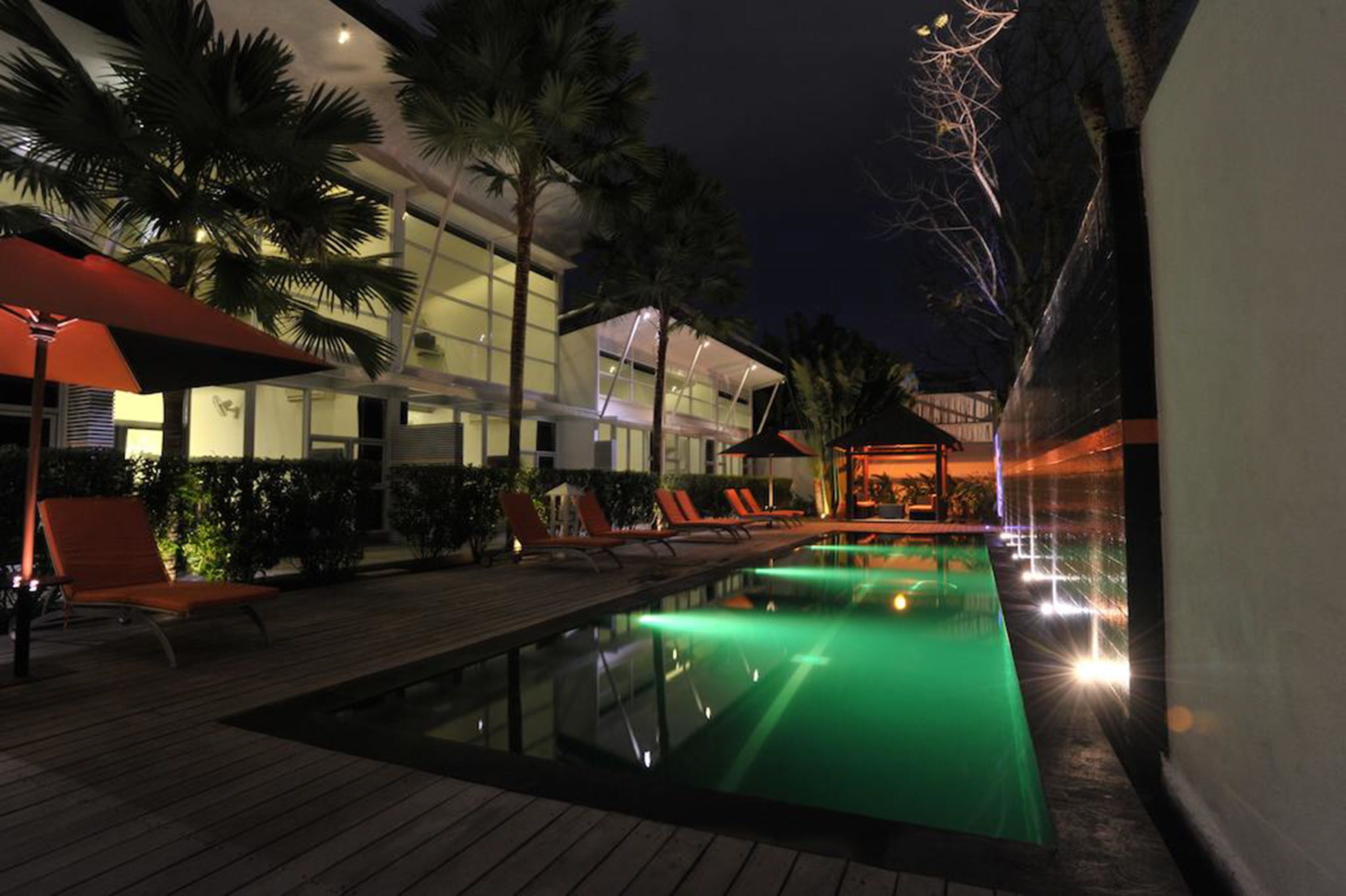 A nighttime pool area with lounge chairs and a building in the background.