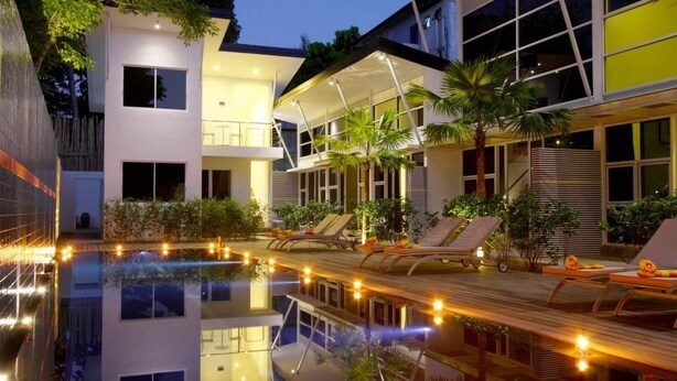 A modern building with a pool, lounge chairs, and a well-lit outdoor area. - Bali Yarra Villas Seminyak (Seminyak)