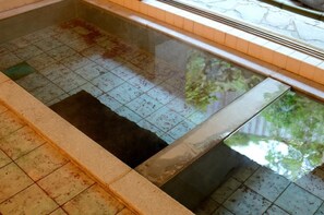 Una piscina con azulejos, una barrera de cristal y un borde de piedra.