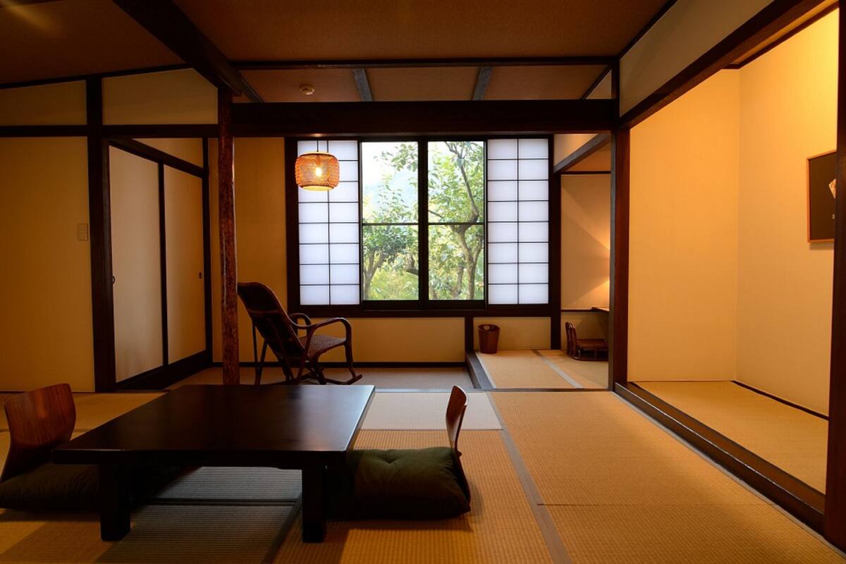 A traditional Japanese room with tatami flooring, a low table, and a window with shoji screens.