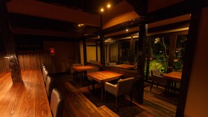 An indoor dining area with wooden tables and chairs, a fire alarm, and large windows overlooking a garden. - Yojokan Haru no Hikari (Hakone)