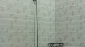 A shower with a handheld showerhead and a wall-mounted faucet. - Puri Ganesh Hotel (Legian)
