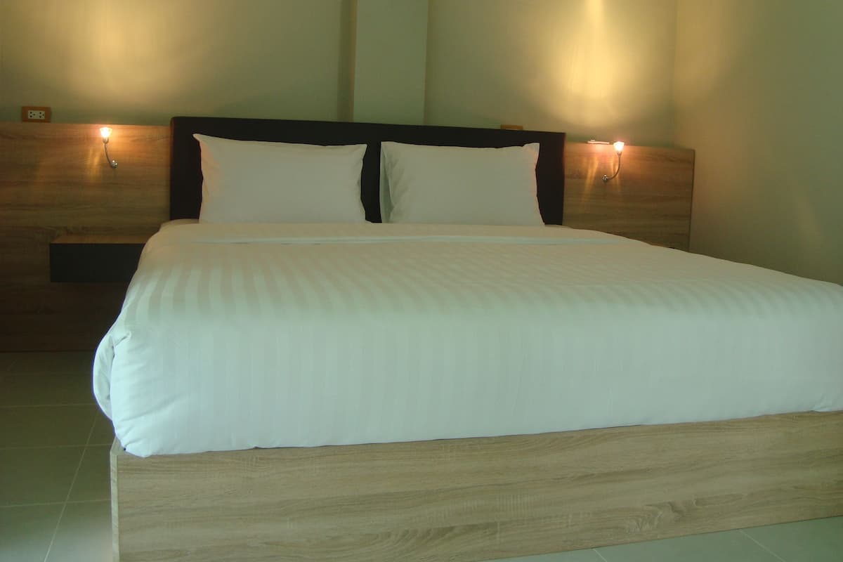 Een keurig opgemaakt bed met een houten hoofdbord en twee wandlampen.
