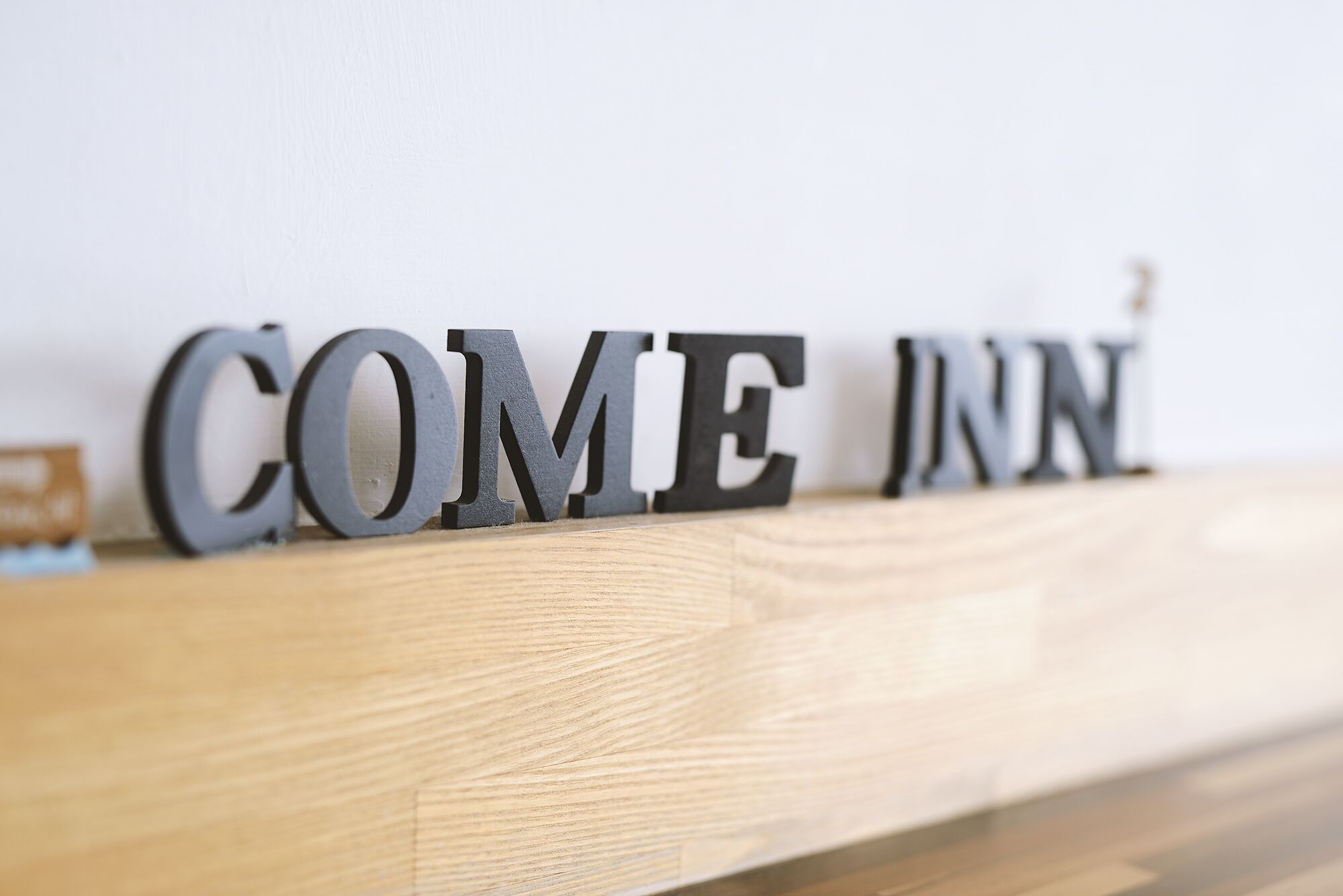 A wooden shelf with metal letters spelling "COME JUNE".
