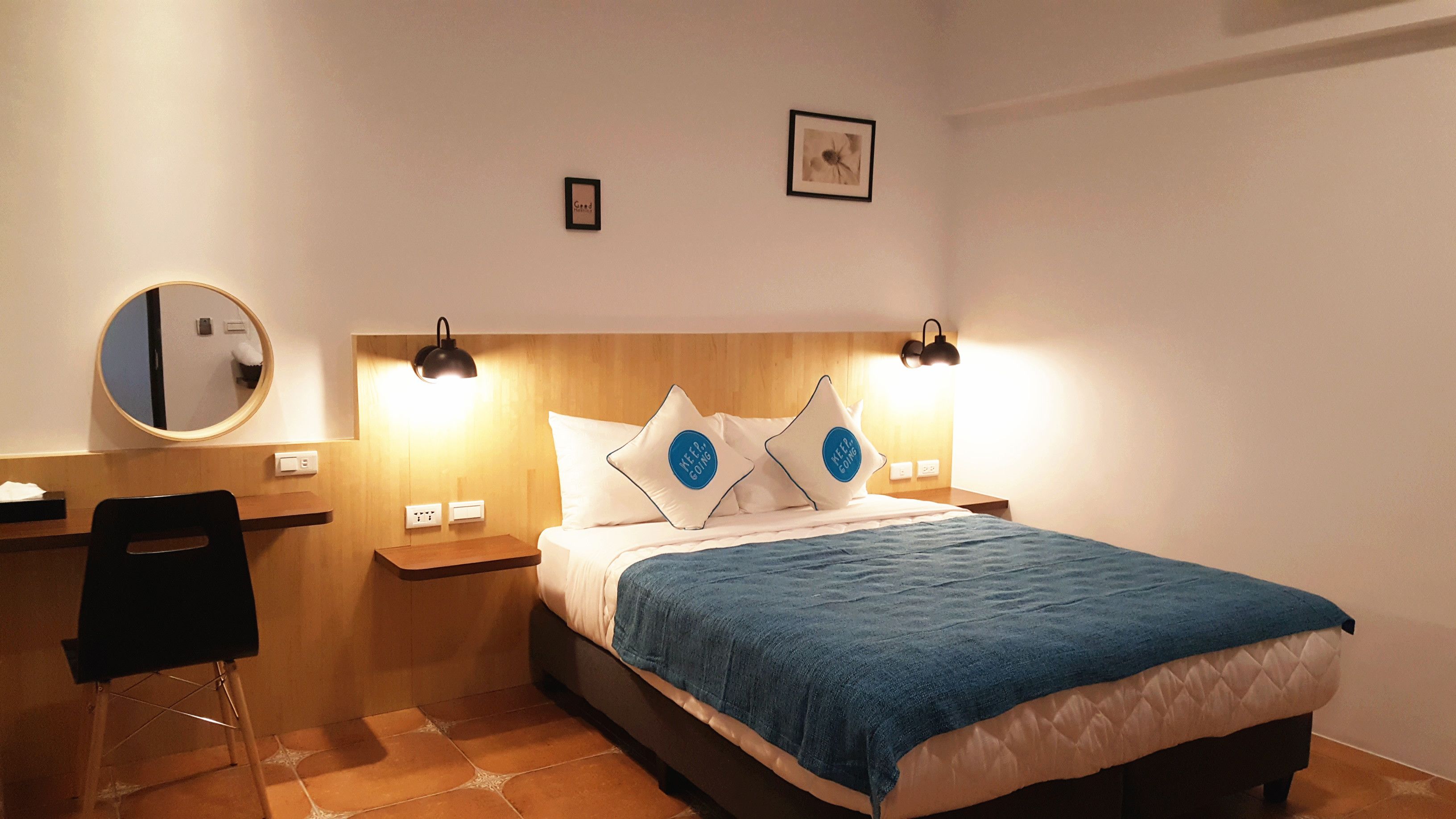 A neatly arranged hotel room with a bed, bedside tables, a mirror, and a chair.