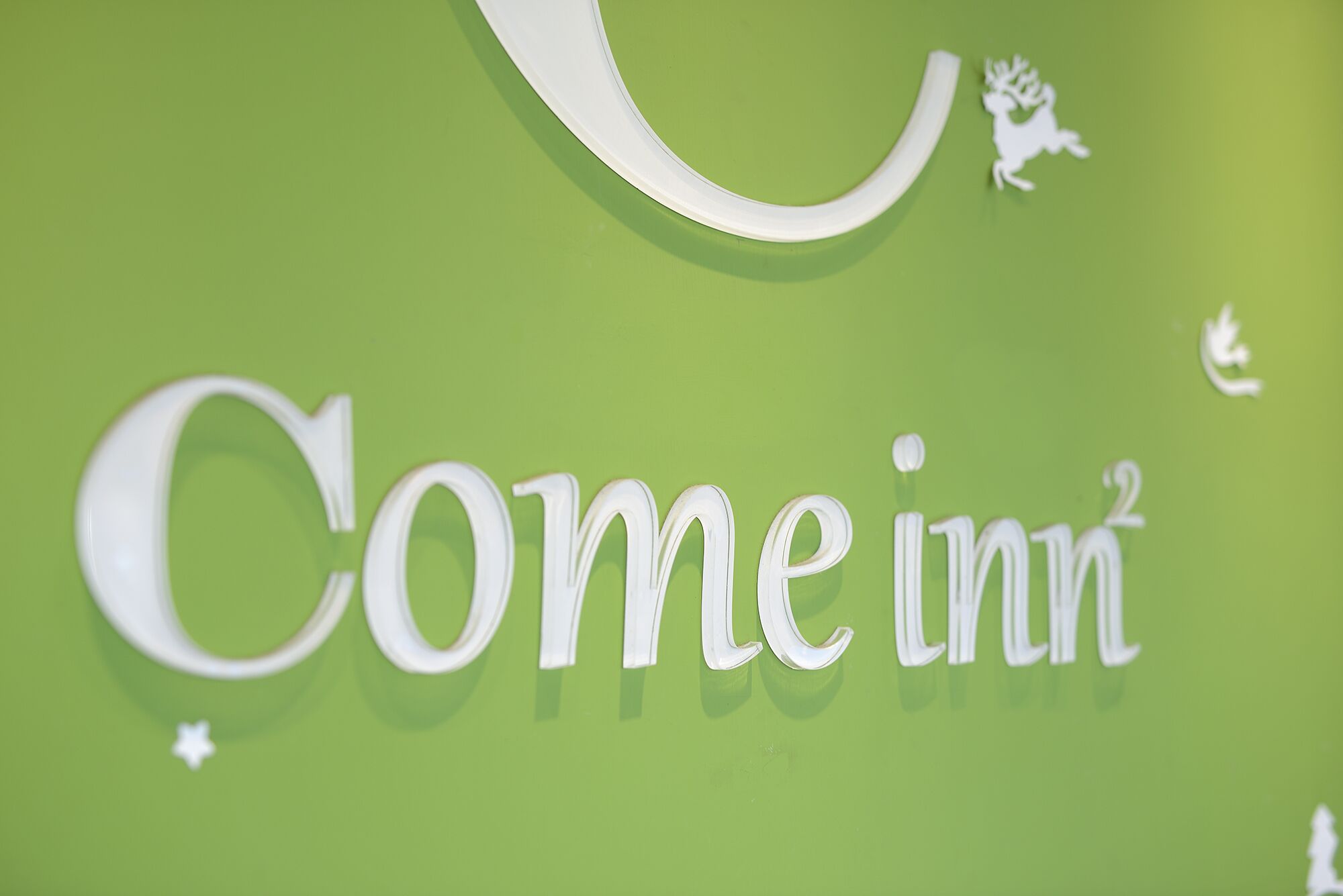 A sign with the text "Comeinn" on a green background.