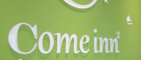 A sign with the text "Comeinn" on a green background.