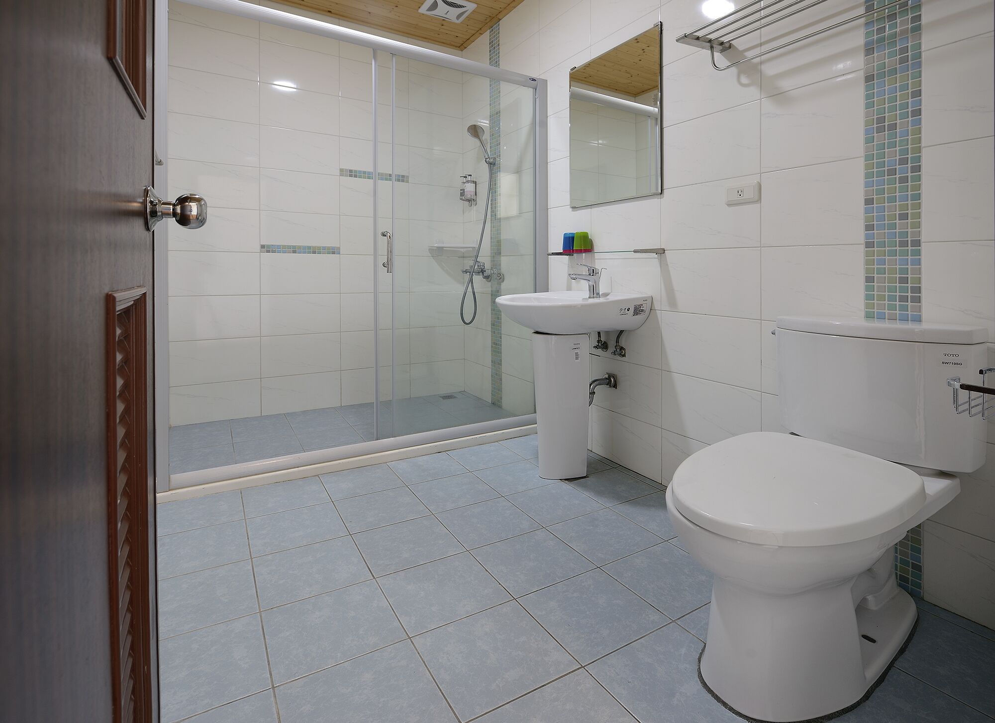 A bathroom with a glass-enclosed shower, a toilet, and a sink.