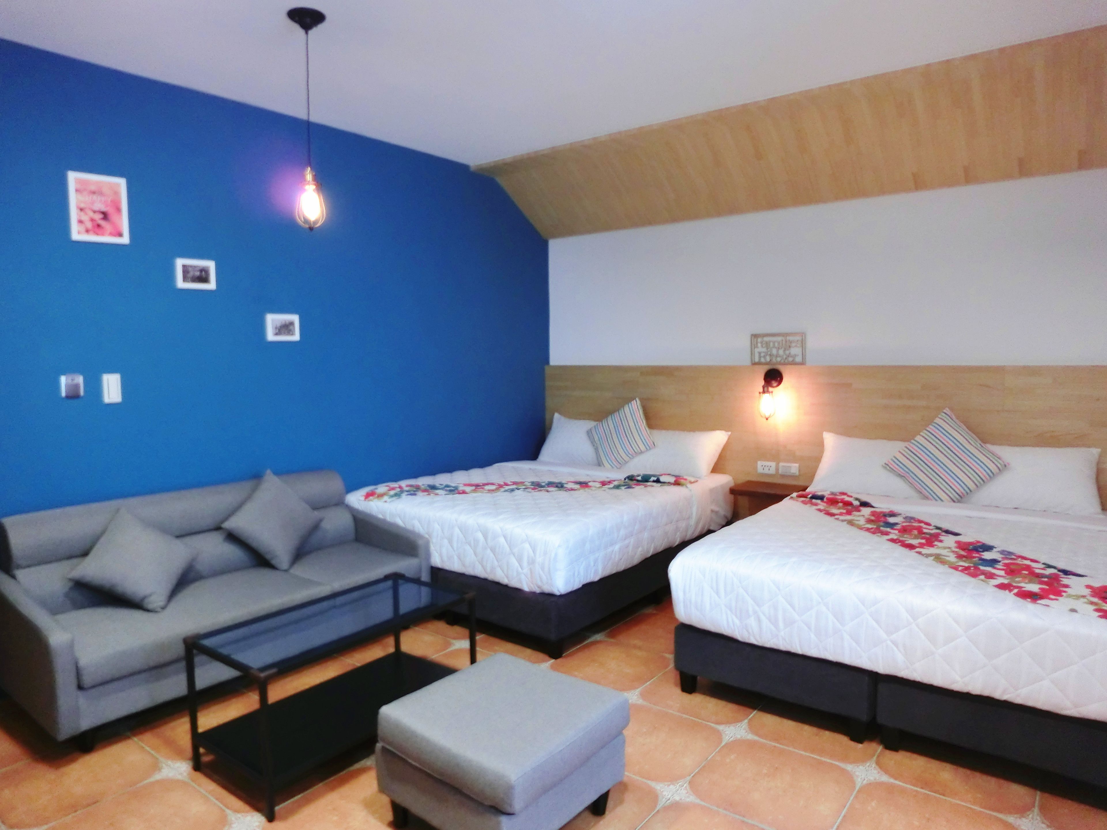 Quarto com duas camas, um sofá e uma mesinha.