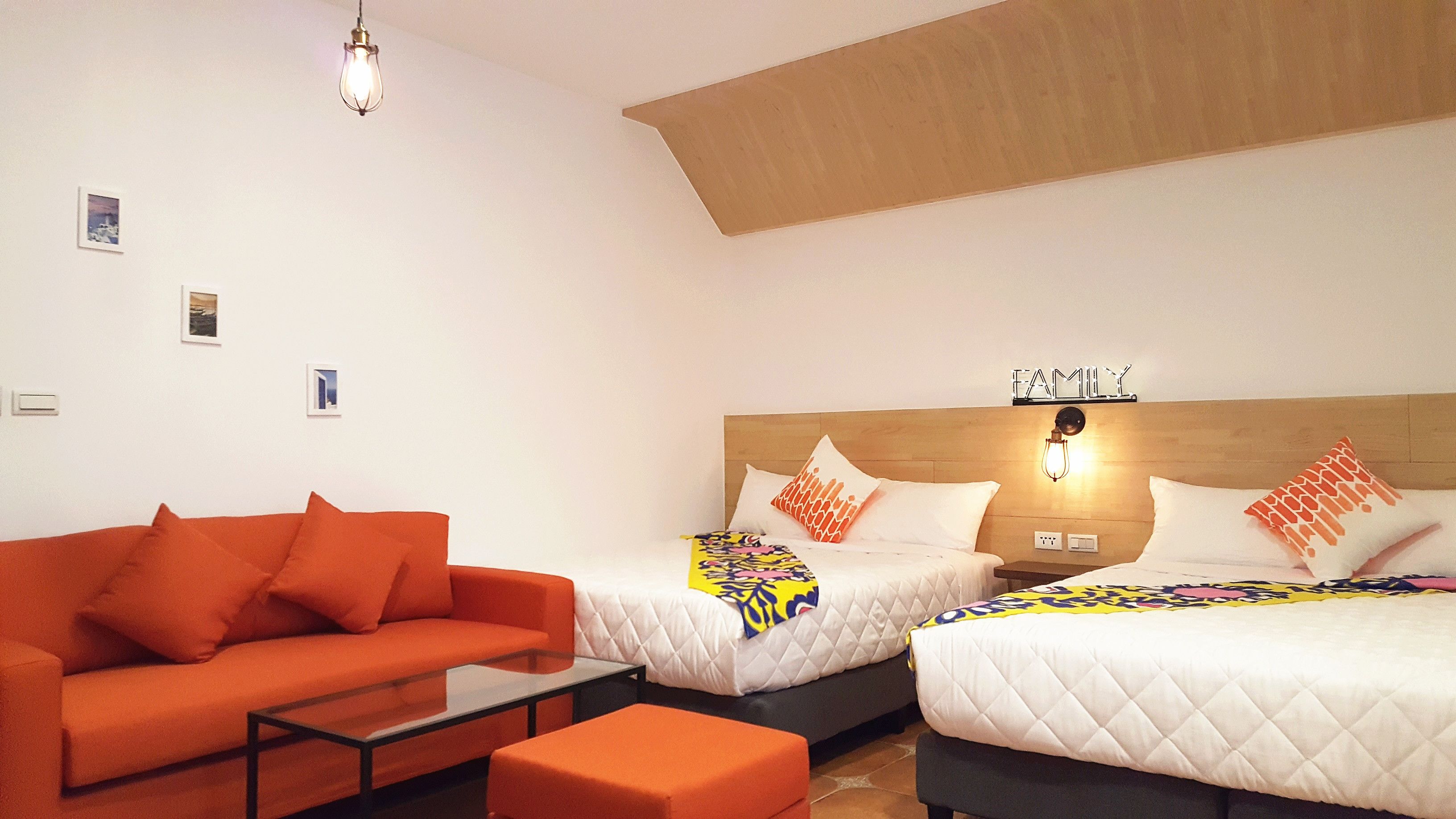 Habitación de hotel con dos camas, un sofá, una mesita de centro y una lámpara en el techo.