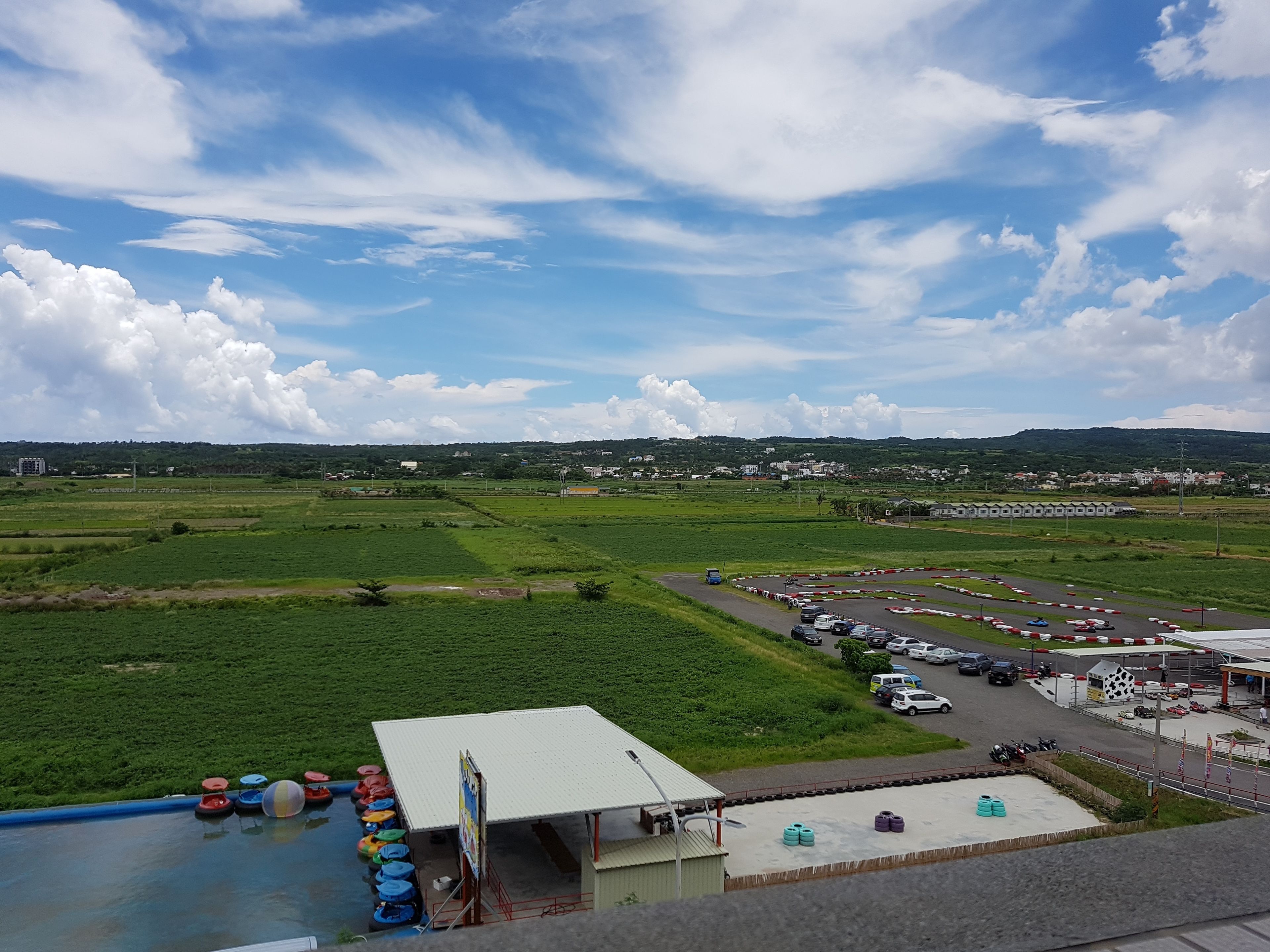 A view of a racing track with a green field in the foreground and a building with a sign.