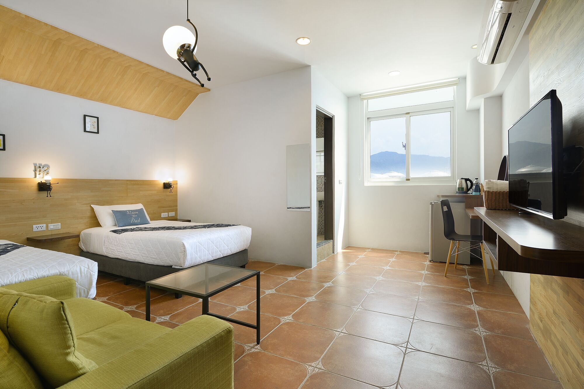 Habitación de hotel con dos camas, un escritorio, un televisor y vistas a las montañas.