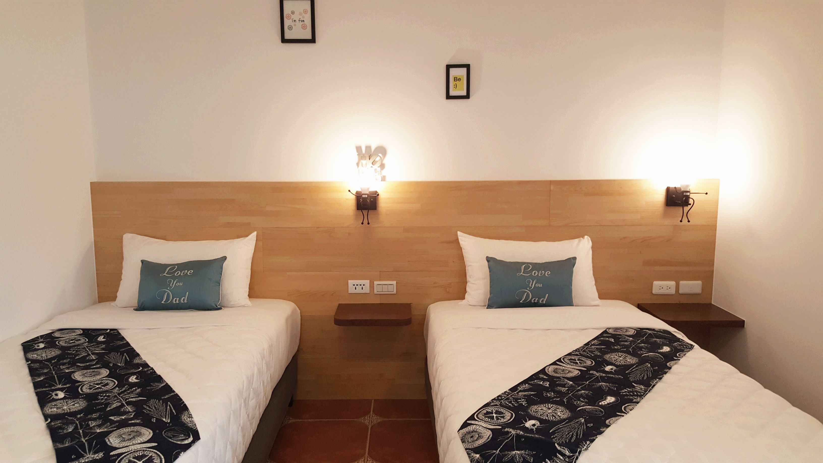 Dos camas individuales con cabeceras, mesitas de noche e iluminación en la pared.