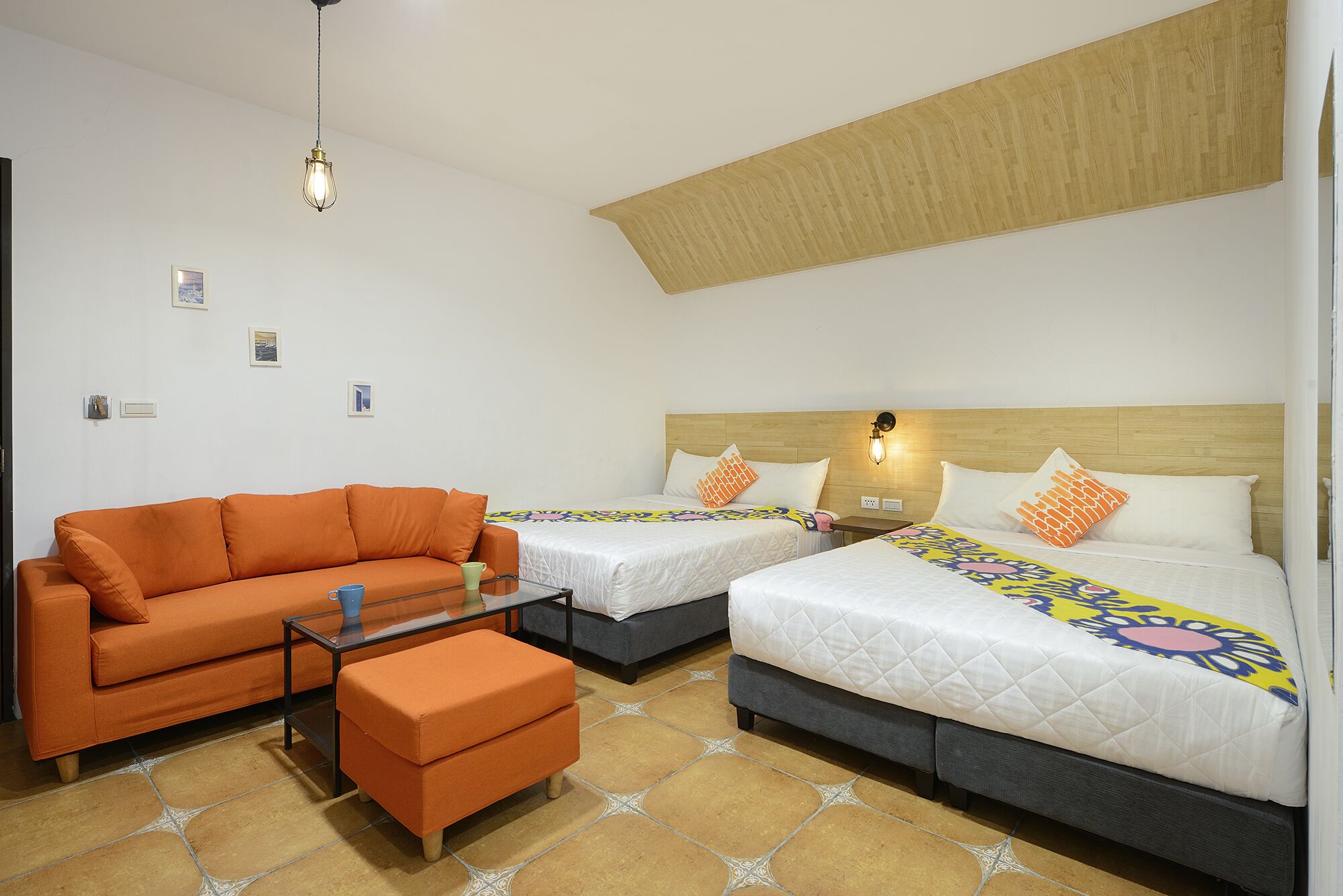 A hotel room with two beds, a sofa, and a small table.
