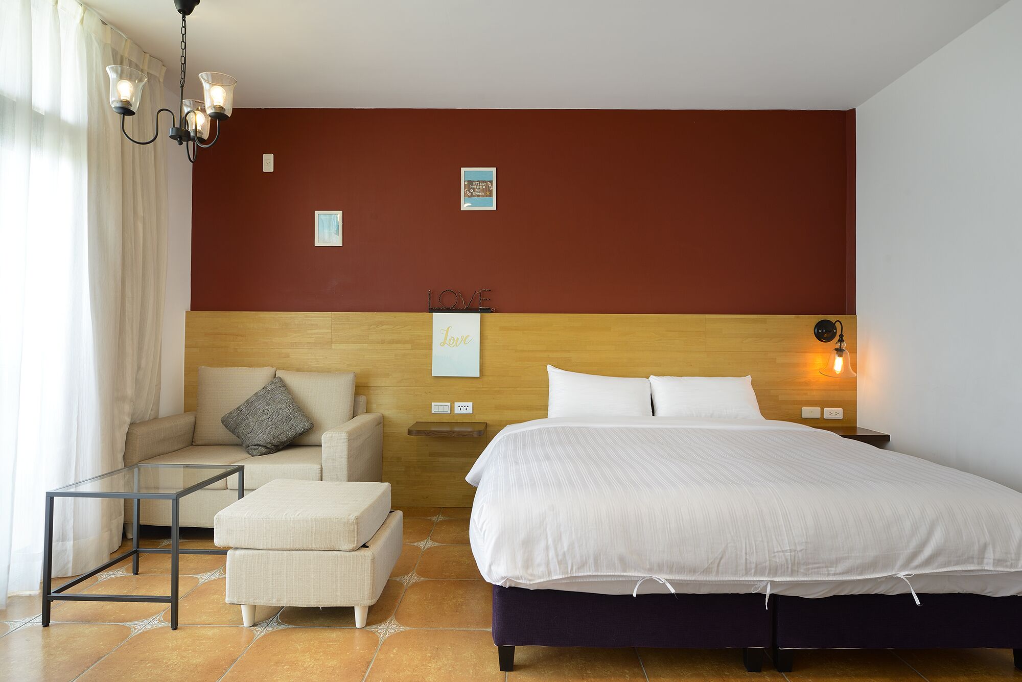 A hotel room with a bed, a sofa, a glass coffee table, and a nightstand.