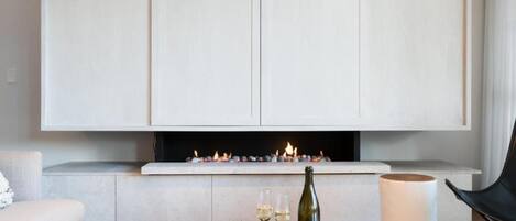 Ein modernes Wohnzimmer mit Kamin, Glastisch und einer Couch.