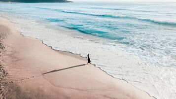 A beach with a person walking along the shore.