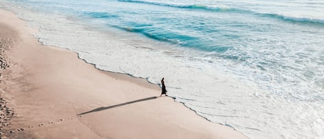 A beach with a person walking along the shore.